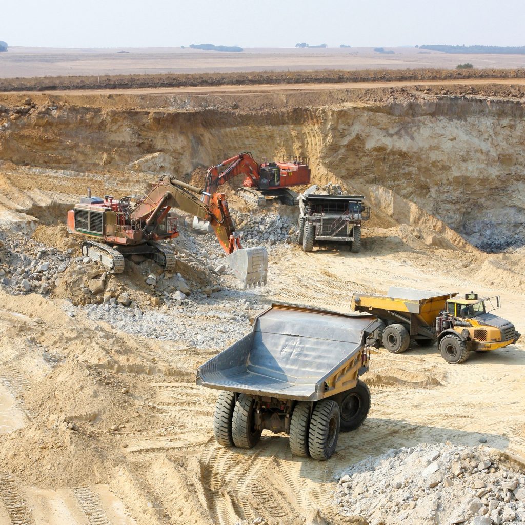 Closeup shot of open pit coal mining with large trucks for digging and transporting raw coal